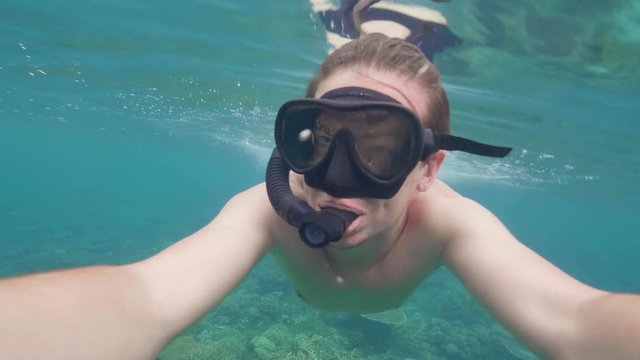 Face young man in snorkeling mask ans snorkel while underwater swimming in blue sea. Selfie video man snorkeler swimming in turquoise ocean water together girl friend. Snorkeling and diving.