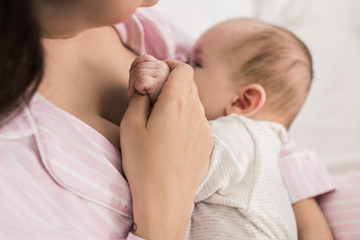 partial view of mother breastfeeding little baby at home