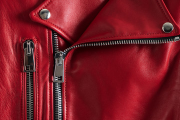 Red leather women's jacket with metallic zipper and buttons. Modern fashionable clothes. Detailed closeup view.