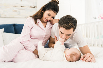 Obraz premium happy parents resting on bed together with cute baby at home