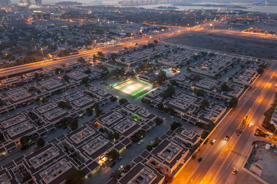 Illuminated tennis courts at Palma Spring Village, Dubai, UAE, in early evening © Glen