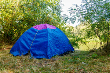 Blue camping tent in forest near a river