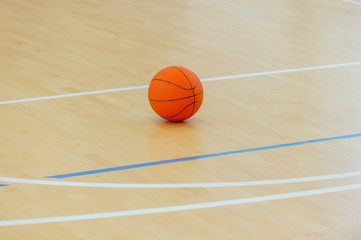 Naklejka premium Basketball on a hardwood court floor as a sports and fitness symbol of a team leisure activity playing with a leather ball dribbling and passing in competition tournaments.