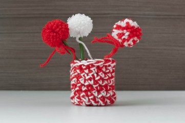 Martenitsa, white and red strains of yarn, Bulgarian folklore tradition, welcoming the spring in March, symbol wish for good health. Baba Marta Day. Crochet vase pompom flowers. Shallow depth.