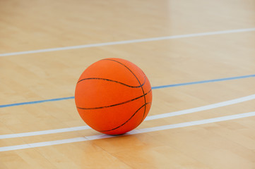 Basketball on a hardwood court floor as a sports and fitness symbol of a team leisure activity playing with a leather ball dribbling and passing in competition tournaments.