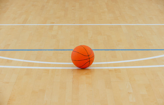 Basketball on a hardwood court floor as a sports and fitness symbol of a team leisure activity playing with a leather ball dribbling and passing in competition tournaments.