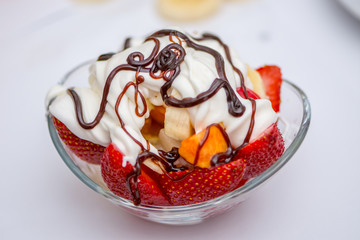 The fruit salat with the cream and chocolate  prepared in the glass bowl
