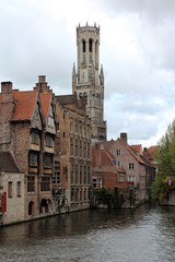 Fototapeta na wymiar Bruges, Belgium. Scenery with water canal and view of Belfry Tower.