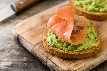 Avocado and salmon toasted breads for breakfast on wooden table

