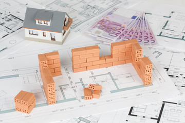 Model house construction with brick on blueprint and five hundred euro banknote