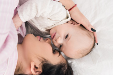 overhead view of mother and little son lying on bed together