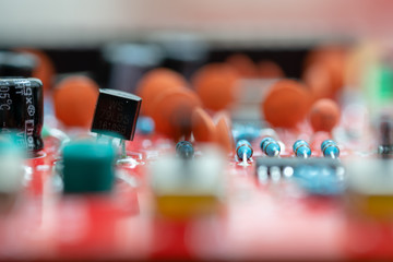 Fototapeta na wymiar Close up (Macro) of Printed Circuit Board PCB embedded components (inductors, resistors, capacitors, diodes, microchips, transistor) with short depth of view