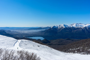 Snowy peaks on a sunny day, with lakes and snowy mountains on the horizon. View of Catedral hill, Bariloche, Argentina.