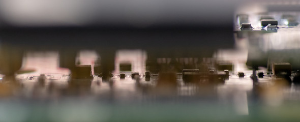 Close up (Macro) of Printed Circuit Board PCB embedded components (inductors, resistors, capacitors, diodes, microchips, transistor) with short depth of view.