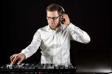 DJ hört Musik über Kopfhörer und mischt die Titel am Mischpult