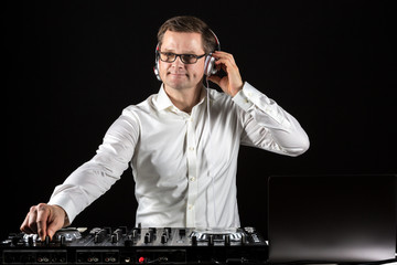 DJ hört Musik über Kopfhörer und mischt die Titel am Mischpult