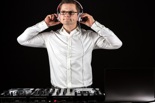 DJ hört Musik über Kopfhörer und mischt die Titel am Mischpult