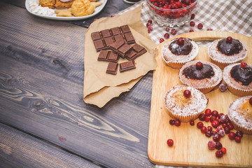 Happy New Year  cranberries, sweets in a dessert plate, a broken chocolate bar on kraft paper and a glass of tea with lemon on a linen napkin on a dark gray background.