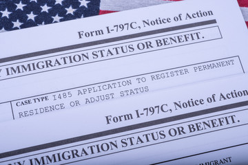 Two Form I - 797C Application to extend change nonimmigrant status (Notice of action, I539, immigration status) on flag of USA background. Diagonal view.
