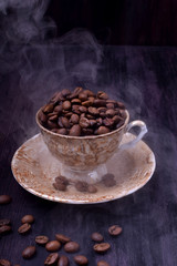 Freshly roasted coffee beans in a cup against the dark wooden background