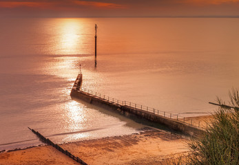 West cliff Ramsgate, uk beach and water breaker walkway late afternoon in winter as the sun is starting to set,making the sea shimmer and the light turn golden