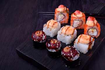 Sushi rolls assortment on a black board