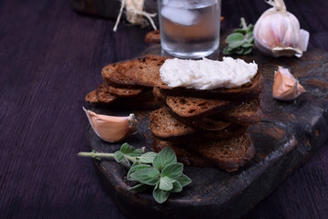 Rye bread toasts, lard paste and a misted glass of vodka on a black board. Ukrainian cuisine appetizer