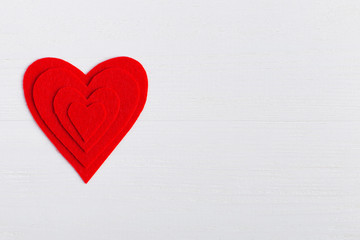 Red hearts of different sizes on a white background. Harvesting cards for Valentine's Day. Place...