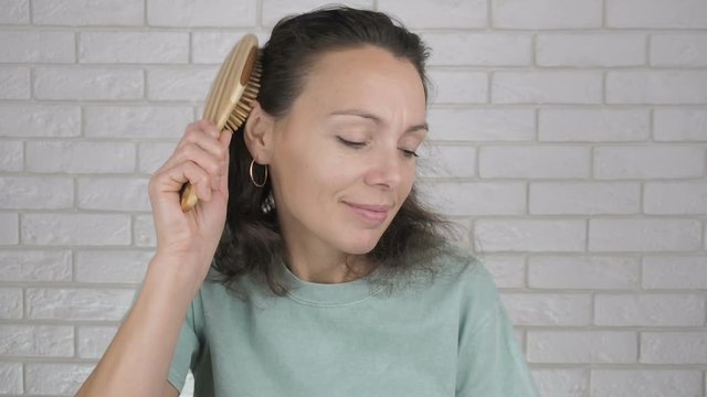 Woman combing. A woman is combing her hair with a wooden brush.