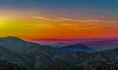 Landscape with orange and purple silhouettes of mountains, hills and forest