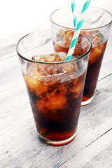Softdrink with ice cubes, lemon and straw in glass