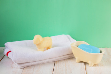 soap in soap dish and lamb soap on towel white on wooden table and turquoise background