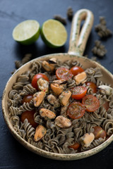 Fusilli made of hemp flour and served with tomatoes and mussels, vertical shot