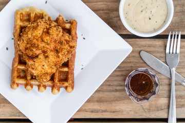 Southern classic meal of chicken and waffles. Fried chicken on top of a Belgian waffle with butter and syrup.  