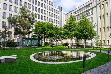 Public park between modern office buildings, future of work, coworking, shared workplace concept, sunny summer day
