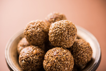 Tilgul Laddu or Til Gul balls for makar sankranti, it's a healthy food made using sesame, crushed peanuts and jaggery. served in a bowl. selective focus showing details.