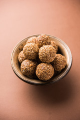 Tilgul Laddu or Til Gul balls for makar sankranti, it's a healthy food made using sesame, crushed peanuts and jaggery. served in a bowl. selective focus showing details.