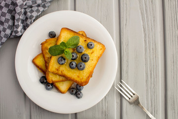 French toasts with blueberries  and honey  in the white  plate on the grey wooden background.Top...