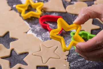 Cooking cookies with cookie cutters on a dark table 