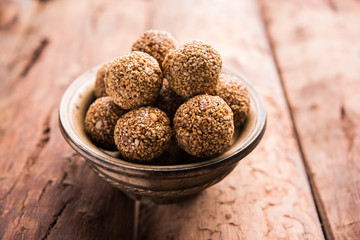 Tilgul Laddu or Til Gul balls for makar sankranti, it's a healthy food made using sesame, crushed peanuts and jaggery. served in a bowl. selective focus showing details.