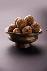 Tilgul Laddu or Til Gul balls for makar sankranti, it's a healthy food made using sesame, crushed peanuts and jaggery. served in a bowl. selective focus showing details.