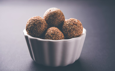 Tilgul Laddu or Til Gul balls for makar sankranti, it's a healthy food made using sesame, crushed peanuts and jaggery. served in a bowl. selective focus showing details.