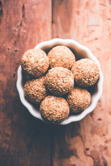 Tilgul Laddu or Til Gul balls for makar sankranti, it's a healthy food made using sesame, crushed peanuts and jaggery. served in a bowl. selective focus showing details.