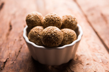 Tilgul Laddu or Til Gul balls for makar sankranti, it's a healthy food made using sesame, crushed peanuts and jaggery. served in a bowl. selective focus showing details.