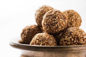 Tilgul Laddu or Til Gul balls for makar sankranti, it's a healthy food made using sesame, crushed peanuts and jaggery. served in a bowl. selective focus showing details.