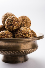Tilgul Laddu or Til Gul balls for makar sankranti, it's a healthy food made using sesame, crushed peanuts and jaggery. served in a bowl. selective focus showing details.