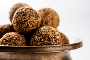 Tilgul Laddu or Til Gul balls for makar sankranti, it's a healthy food made using sesame, crushed peanuts and jaggery. served in a bowl. selective focus showing details.