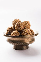 Tilgul Laddu or Til Gul balls for makar sankranti, it's a healthy food made using sesame, crushed peanuts and jaggery. served in a bowl. selective focus showing details.