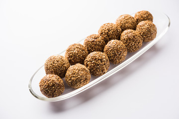 Tilgul Laddu or Til Gul balls for makar sankranti, it's a healthy food made using sesame, crushed peanuts and jaggery. served in a bowl. selective focus showing details.