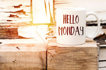 text HELLO MONDAY on cup of aromatic coffee on wooden cube